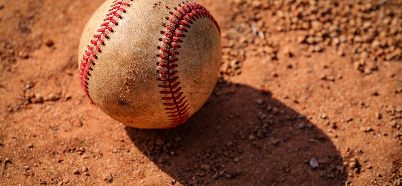 An old baseball is lying in the dirt.