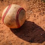 An old baseball is lying in the dirt.