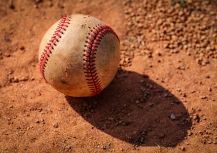 An old baseball is lying in the dirt.