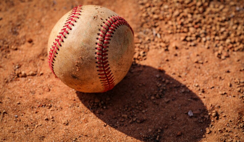 An old baseball is lying in the dirt.