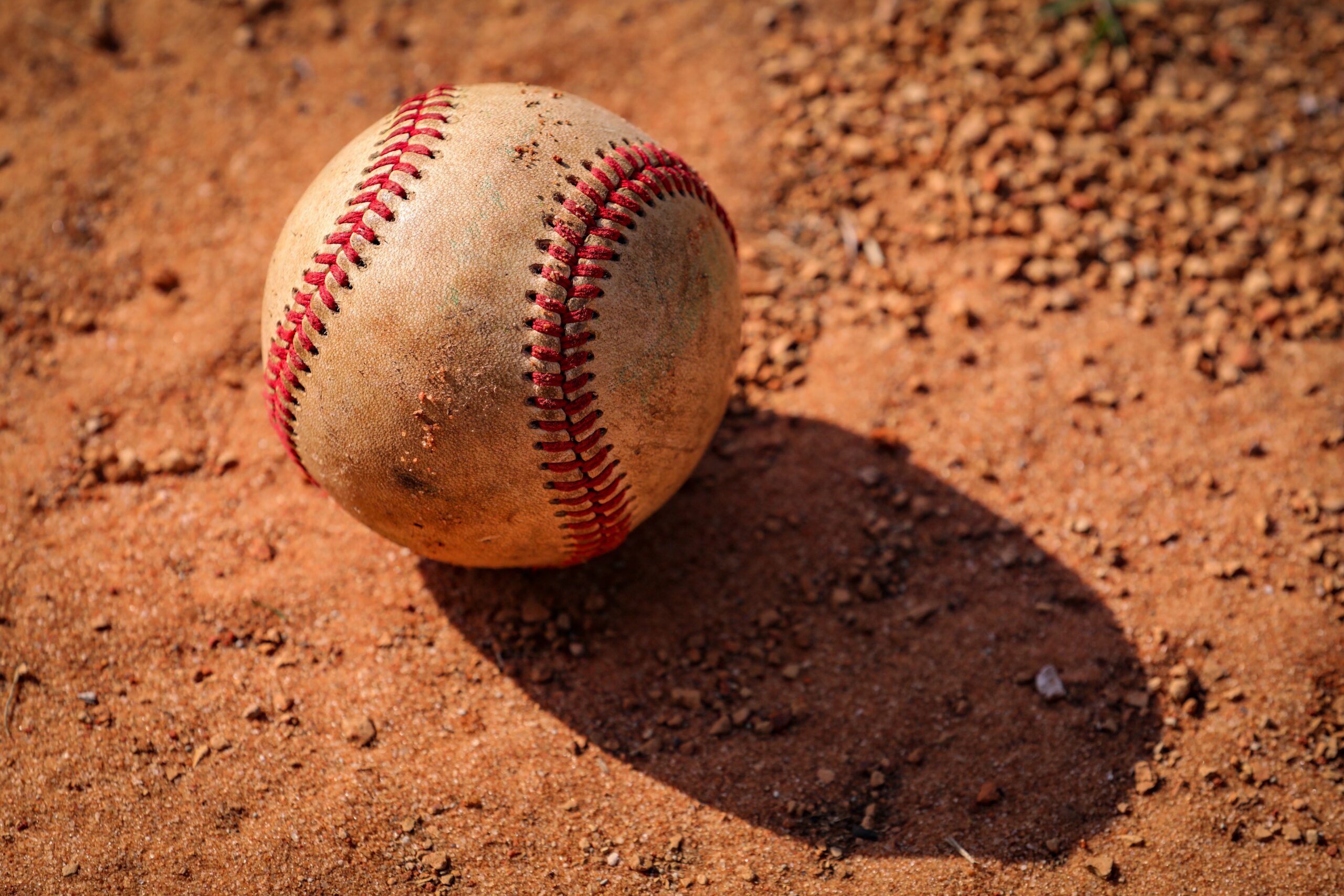 An old baseball is lying in the dirt.