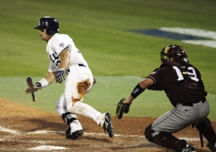 A baseball player begins running to first while dropping his bat.