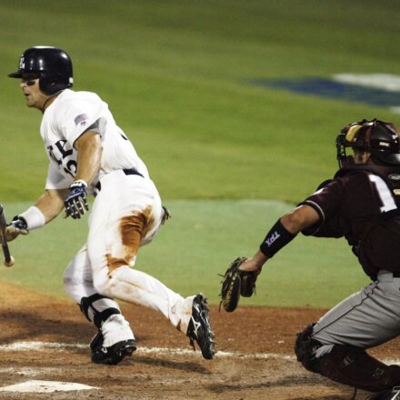 A baseball player begins running to first while dropping his bat.