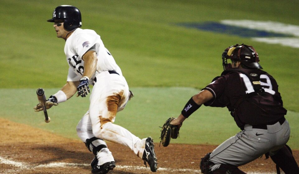 A baseball player begins running to first while dropping his bat.