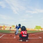 A catcher crouches behind the batter at home plate.