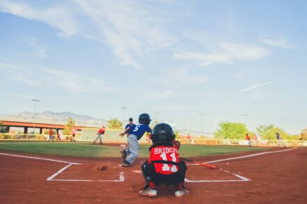 A catcher crouches behind the batter at home plate.