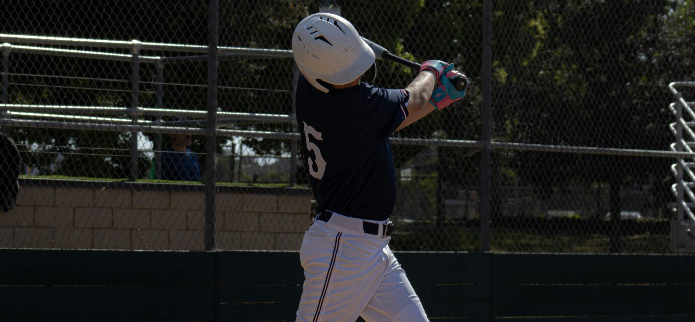 A baseball player takes a swing while at home plate.