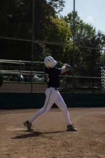 A baseball player takes a swing while at home plate.