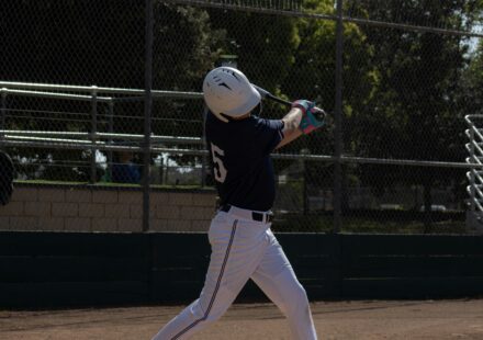 A baseball player takes a swing while at home plate.