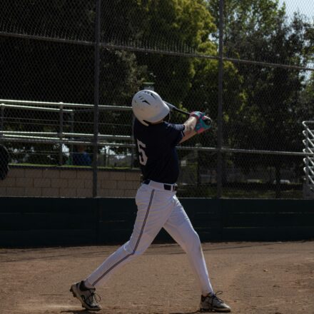 A baseball player takes a swing while at home plate.