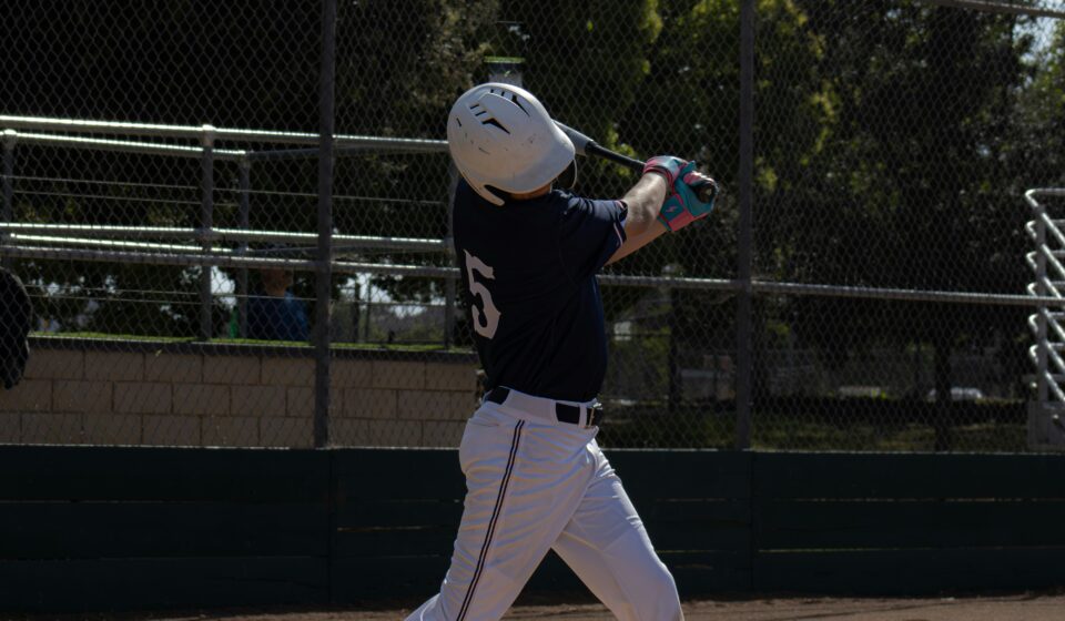 A baseball player takes a swing while at home plate.