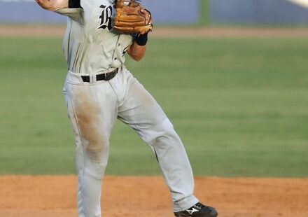 A baseball player leaps while throwing the ball.
