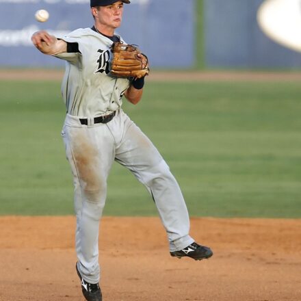 A baseball player leaps while throwing the ball.