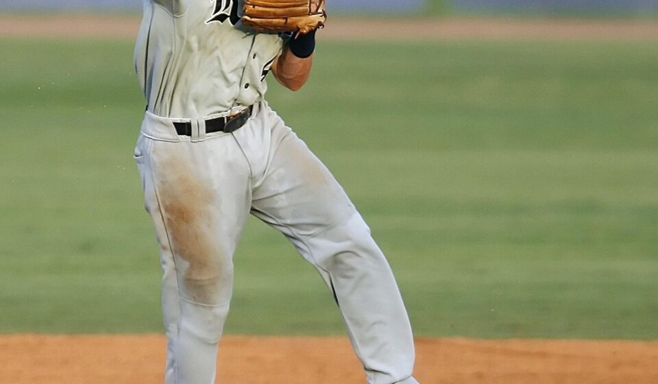 A baseball player leaps while throwing the ball.