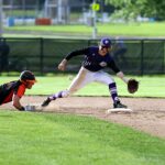 A baseball player slides into the base to avoid being tagged out.