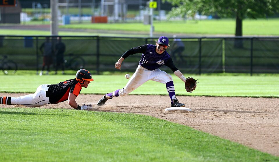 A baseball player slides into the base to avoid being tagged out.