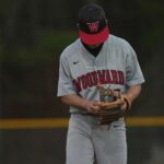A baseball player looks down at his glove.