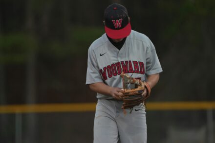 A baseball player looks down at his glove.