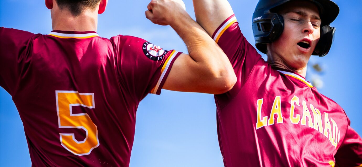 Two baseball players raise their arms triumphantly.