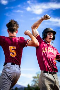 Two baseball players raise their arms triumphantly.