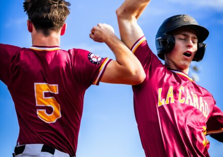 Two baseball players raise their arms triumphantly.