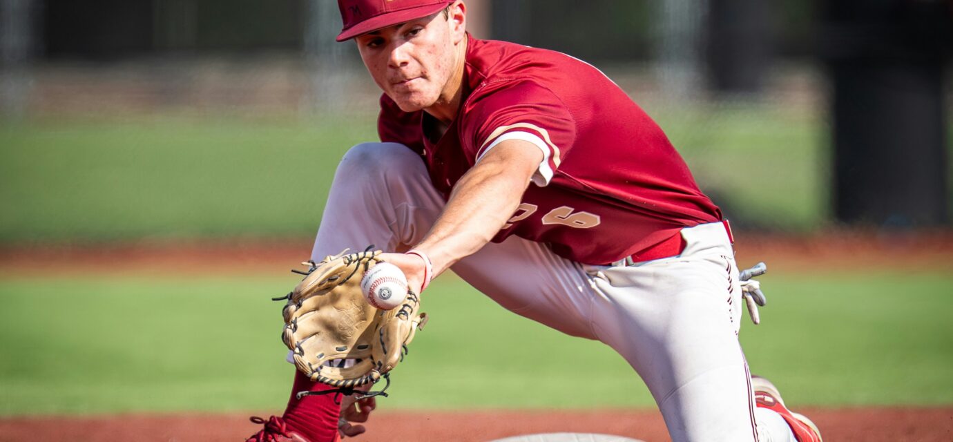 A baseball player reaches out to catch the ball with his mitt.