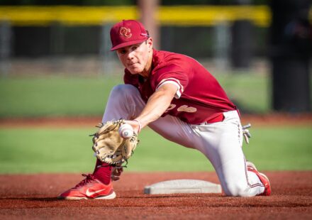 A baseball player reaches out to catch the ball with his mitt.