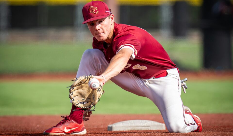 A baseball player reaches out to catch the ball with his mitt.
