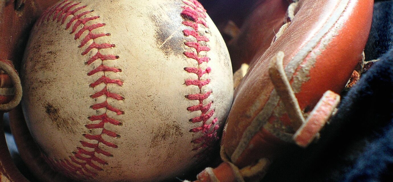 A smudged baseball rests in a baseball glove.