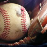 A smudged baseball rests in a baseball glove.