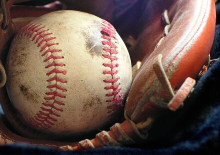 A smudged baseball rests in a baseball glove.