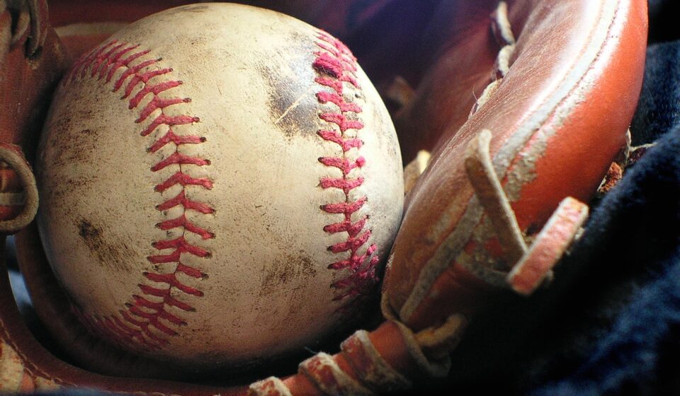 A smudged baseball rests in a baseball glove.