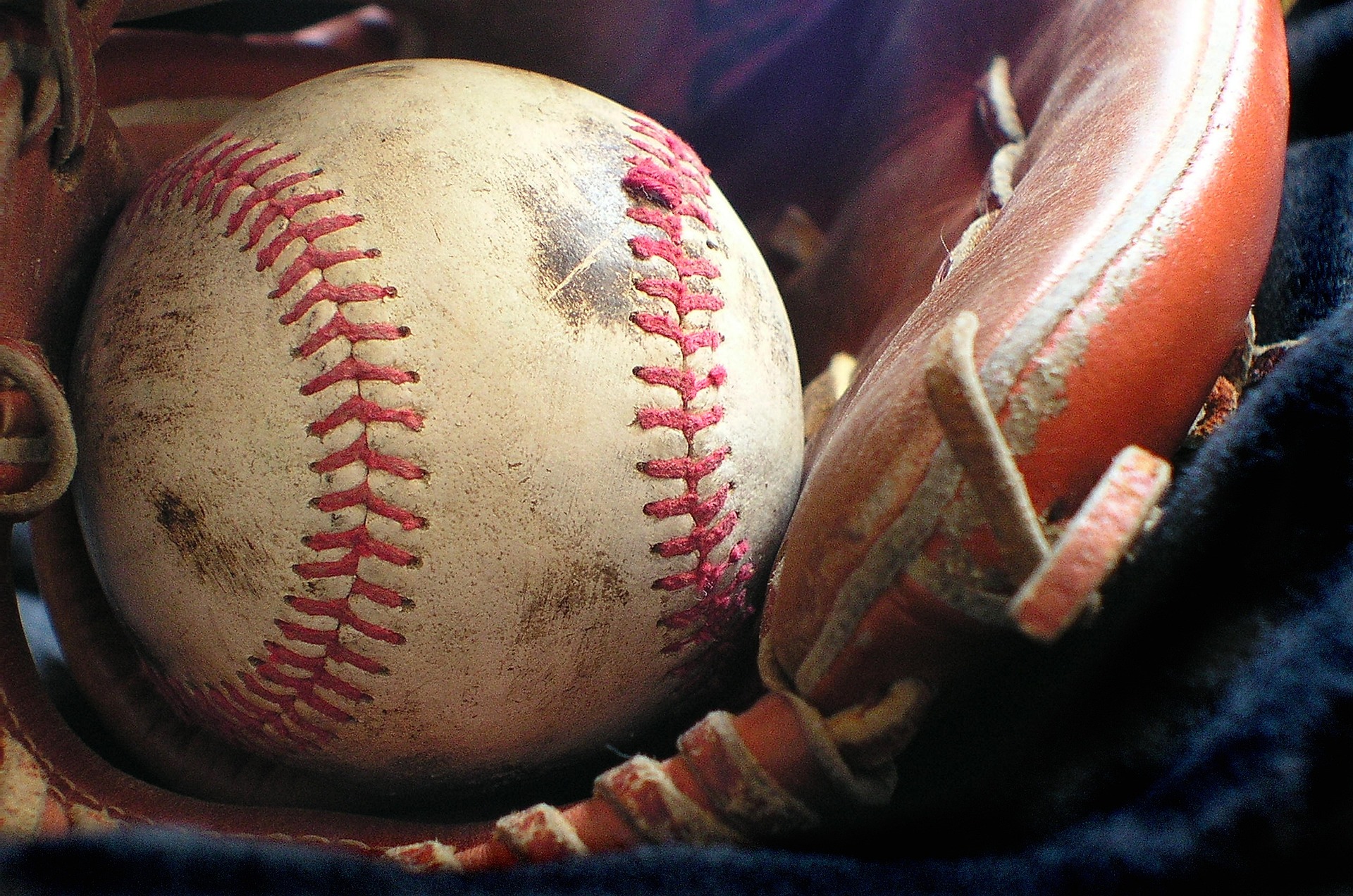 A smudged baseball rests in a baseball glove.