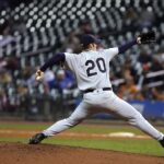 A pitcher extends to hurl the ball toward home plate.