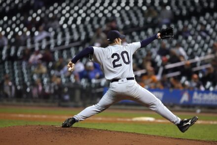 A pitcher extends to hurl the ball toward home plate.