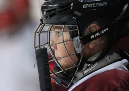 A baseball catcher looks out through his face mask.