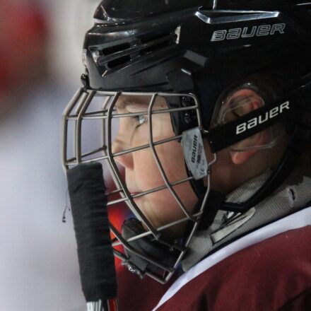 A baseball catcher looks out through his face mask.