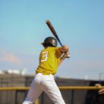 A baseball player raises his bat, ready for the pitch.