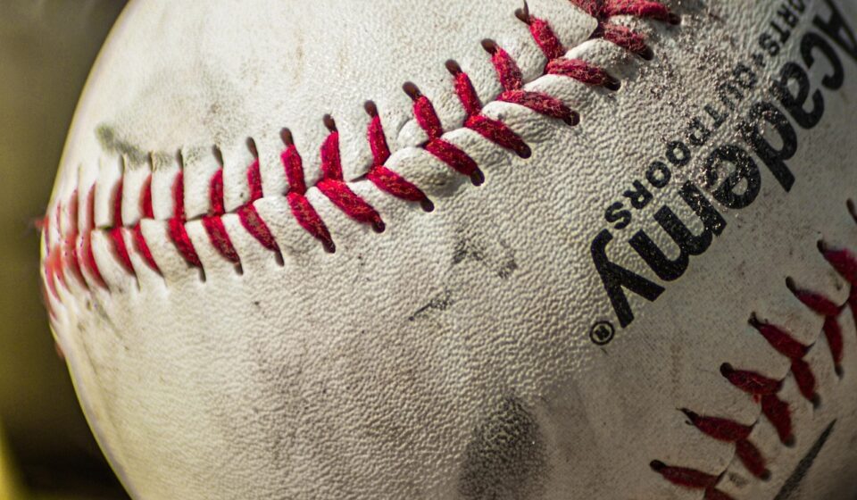 Several baseballs rest in the grass.