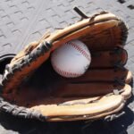 A baseball hides inside of a baseball glove.