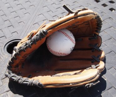 A baseball hides inside of a baseball glove.