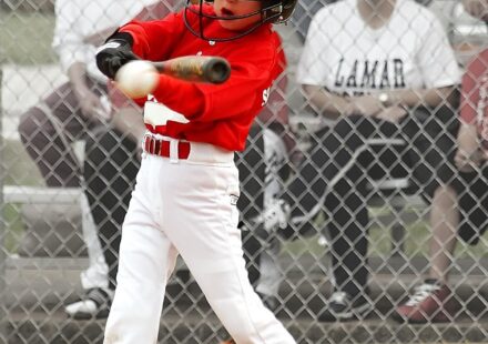 A batter at home plate swings at the ball.