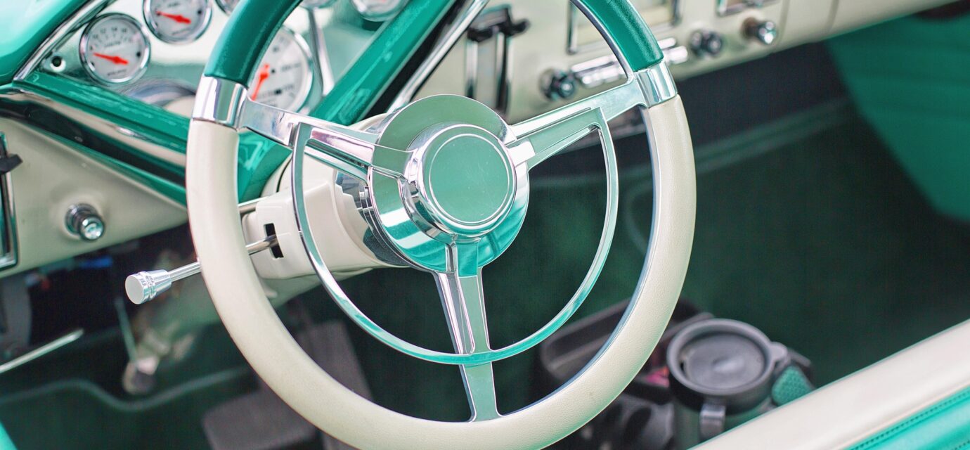 The interior of a classic vehicle in aqua and white.