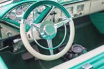 The interior of a classic vehicle in aqua and white.
