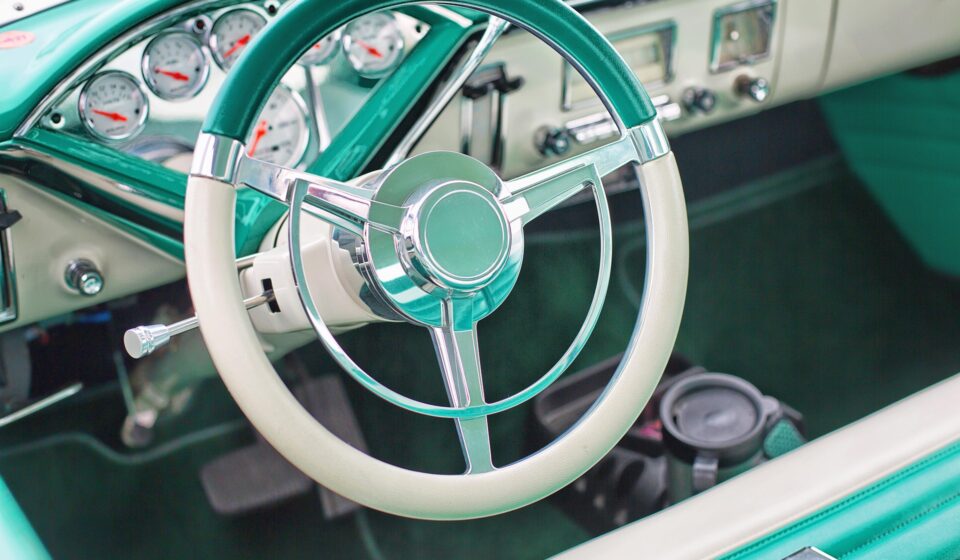 The interior of a classic vehicle in aqua and white.