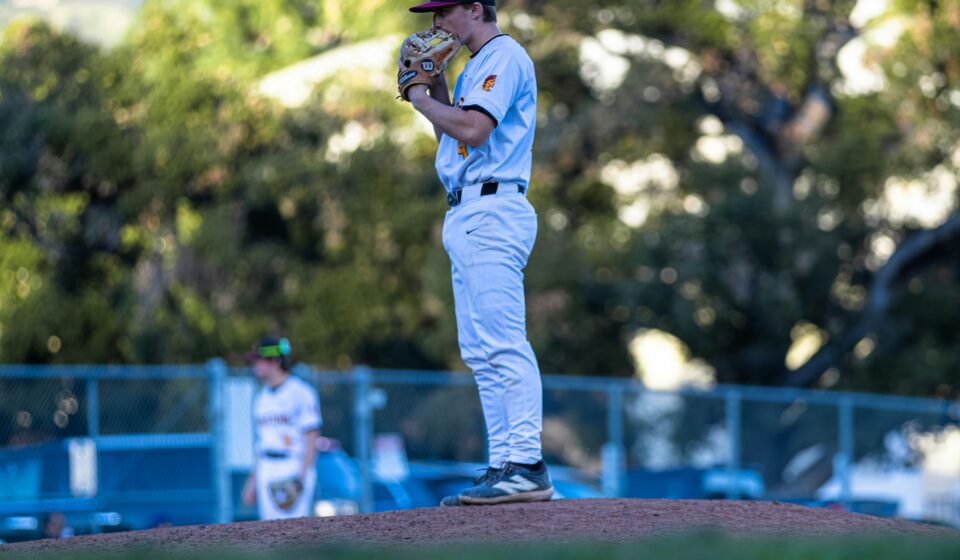 A pitcher stands on a mound in a baseball field.