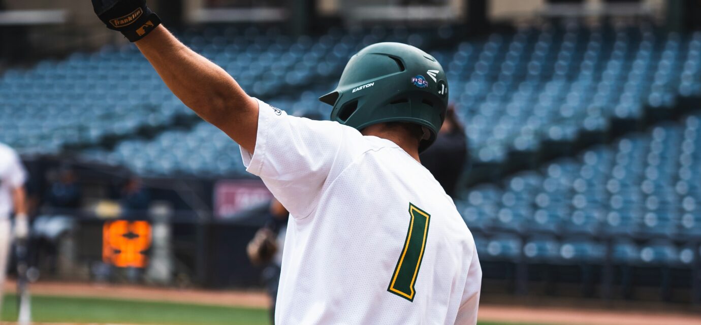A baseball player swings a bat over his head.