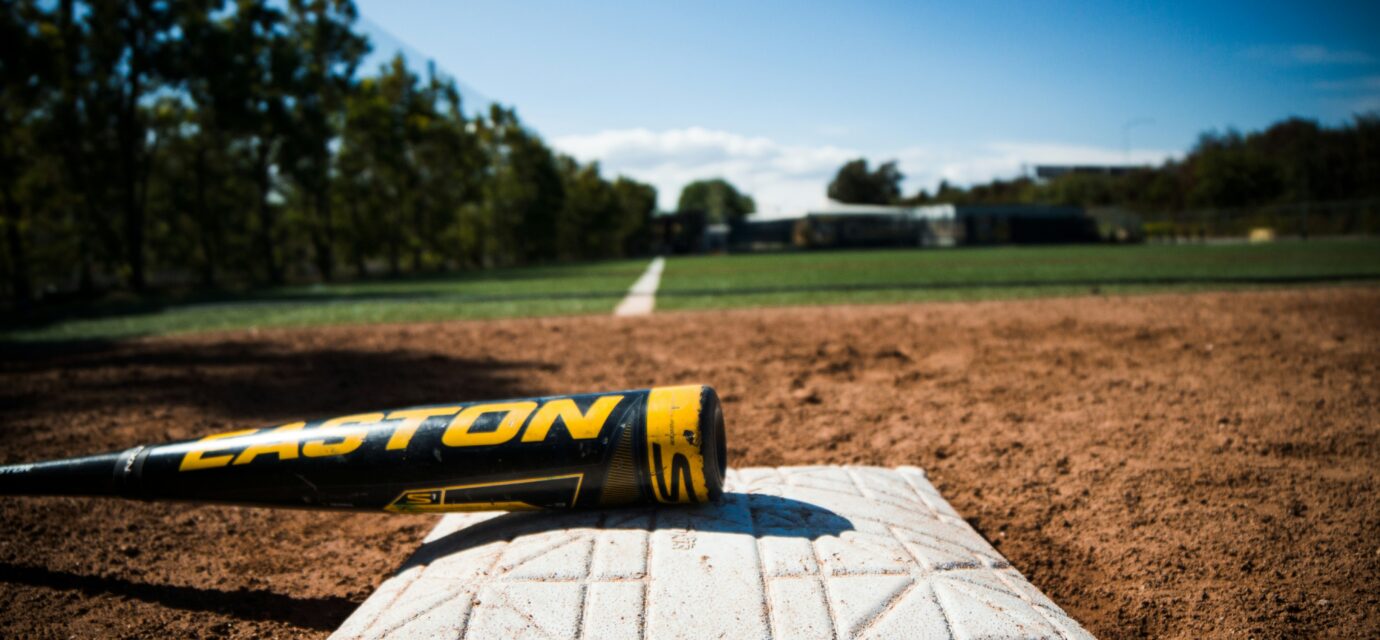 A bat lies on a base on a baseball field.