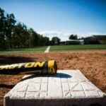 A bat lies on a base on a baseball field.