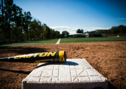 A bat lies on a base on a baseball field.